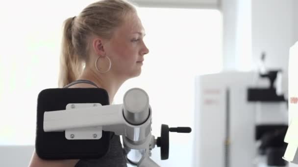 Junge Frau macht Übungen am Simulator im Physiotherapieraum — Stockvideo