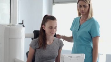 Spor salonunda terapistle simülatör üzerinde egzersiz yapan genç bir kadın.