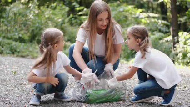 Kvinna och två små flickor samlar skräp i skogen — Stockvideo