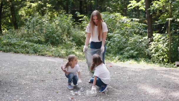 Γυναίκα και δύο κοριτσάκια μαζεύουν σκουπίδια στο δάσος. — Αρχείο Βίντεο