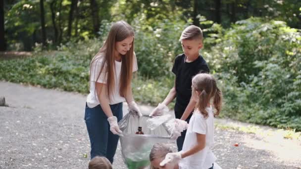 Grupa dzieciaków w rękawiczkach zbierających śmieci w parku miejskim — Wideo stockowe