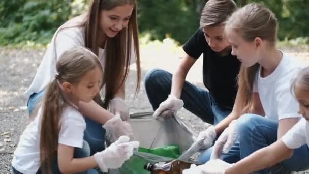 Grupo de niños en guantes recogiendo la basura en el parque de la ciudad — Vídeo de stock