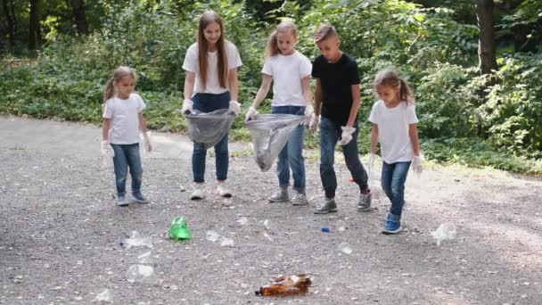 Şehir parkındaki çöpleri toplayan eldivenli bir grup çocuk. — Stok video