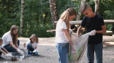 Genç gönüllü bir grup çocuk ormanda çöp topluyor.