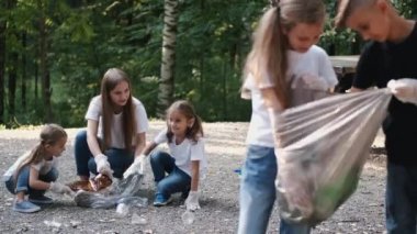 Genç gönüllü bir grup çocuk ormanda çöp topluyor.
