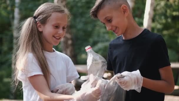 Portré fiú és lány gyűjtése műanyag a városi parkban — Stock videók