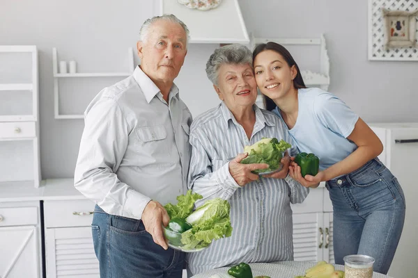 Casal velho em uma cozinha com a jovem neta — Fotografia de Stock