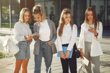 Elinde kitaplarla çimlerin üzerinde yatan üç öğrenci.