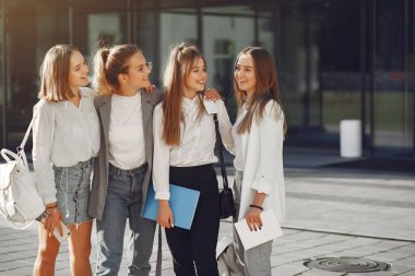 Elinde kitaplarla çimlerin üzerinde yatan üç öğrenci.