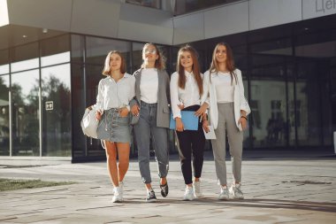 Elinde kitaplarla çimlerin üzerinde yatan üç öğrenci.