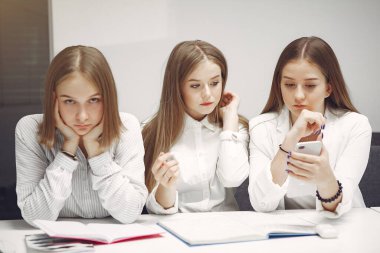 Sınıfta masada oturan üç öğrenci.