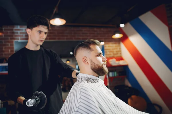 Elegante hombre sentado en una barbería — Foto de Stock