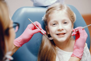 Sevimli küçük kız dişçi ofisinde oturuyor