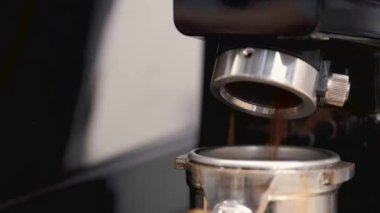 The barista is having the espresso beans grinded in a machine and poured into tamper