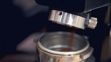 The barista is having the espresso beans grinded in a machine and poured into tamper