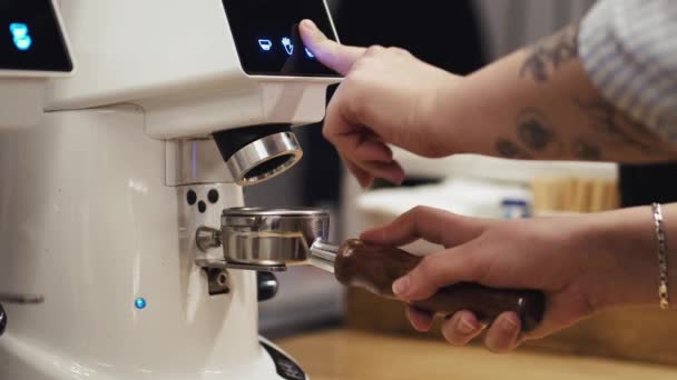 El camarero está moliendo los granos de espresso en una máquina y se vierte en la manipulación — Vídeos de Stock