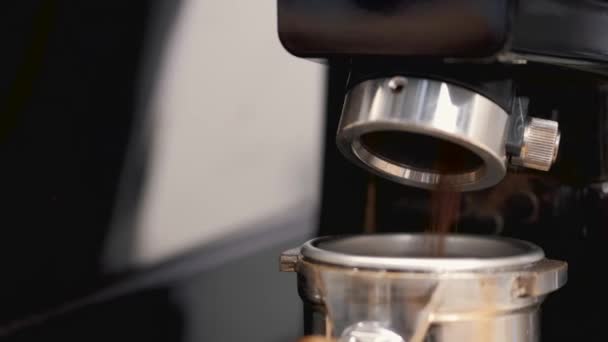 The barista is having the espresso beans grinded in a machine and poured into tamper — Stockvideo