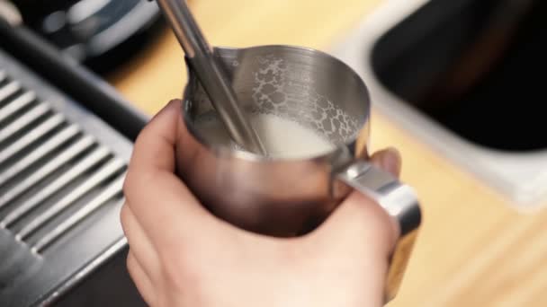 The barista is preparing steamy milk for latte in a coffee machine — Stockvideo