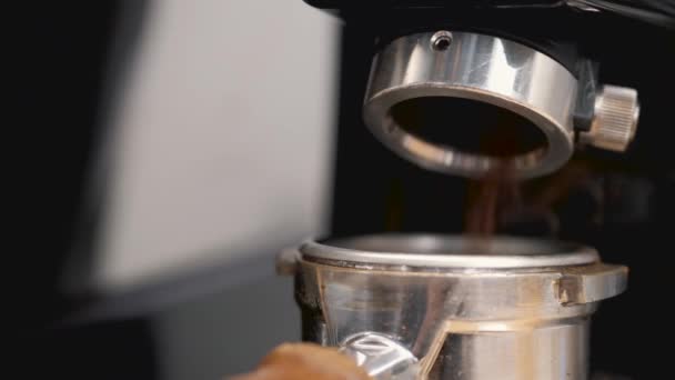 El camarero está moliendo los granos de espresso en una máquina y se vierte en la manipulación — Vídeos de Stock