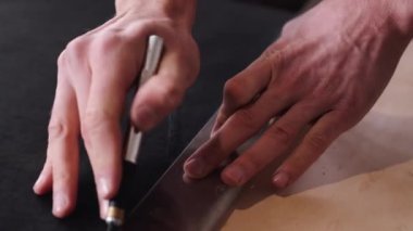 The tanner is cutting black leather sheet with a razor and metre