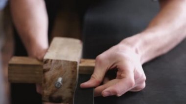 The craftsman is making a leather belt
