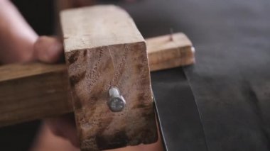 The craftsman is making a leather belt
