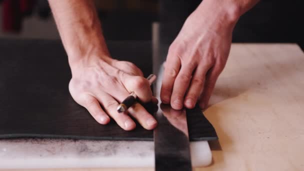 The tanner is cutting black leather sheet with a razor and metre — Stok video