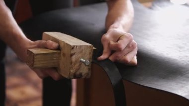 The craftsman is making a leather belt