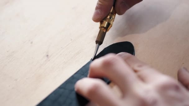 The leather craftsman is cutting the edges of a belt — Stok video