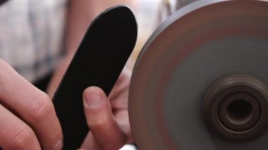 The craftsman is sharpening the edges of a belt on a special machine