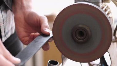 The craftsman is sharpening the edges of a belt on a special machine