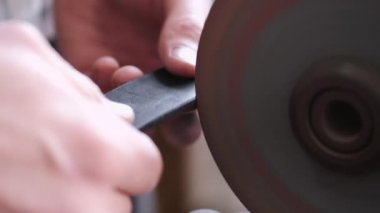 The craftsman is sharpening the edges of a belt on a special machine