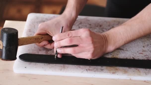 The leather craftsman is making holes in a hand-made belt — Stok video