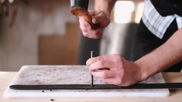 The leather craftsman is making holes in a hand-made belt — Stockvideo