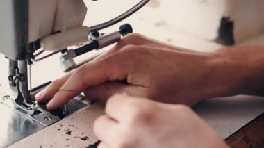 The master is preparing a sewing machine for work