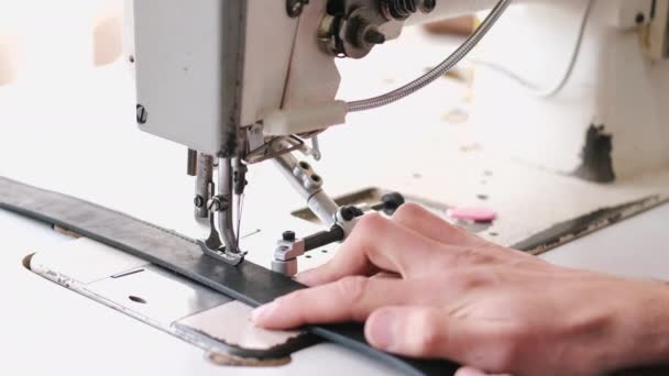 Ремісник зшиває чоловічий шкіряний пояс на швейній машинці — стокове відео