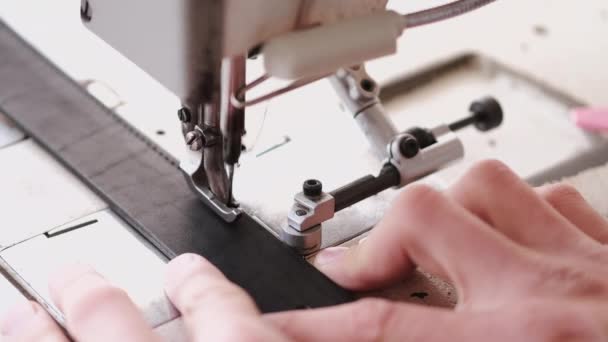 The craftsman stitches a mens leather belt on a sewing machine — 비디오