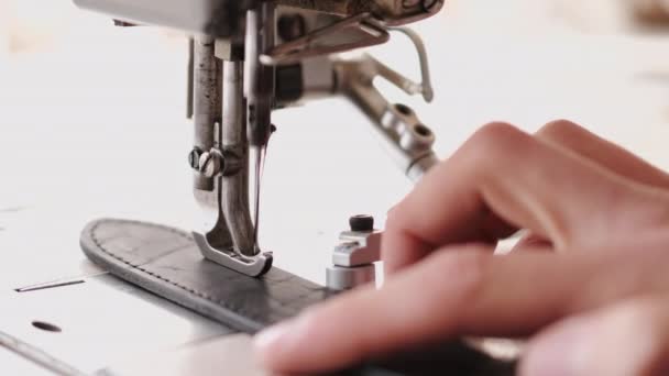 Ремесленник накладывает мужской кожаный ремень на швейную машинку — стоковое видео