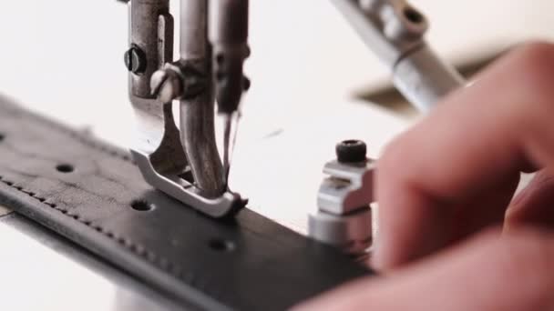 The craftsman stitches a mens leather belt on a sewing machine — Stock video