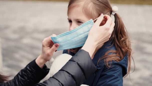 Een vrouw met een wegwerpmasker leert haar kind een masker te dragen. — Stockvideo