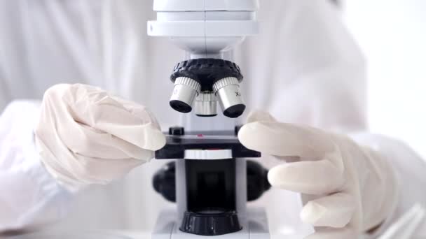 Научный сотрудник настраивает микроскоп в лаборатории — стоковое видео