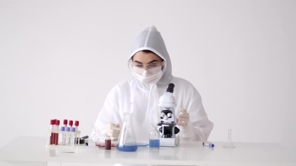 Un trabajador de laboratorio está haciendo una investigación y ajustando un microscopio — Vídeos de Stock