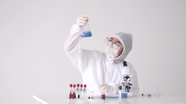 Bir laboratuvar çalışanı bir araştırma yapıyor ve çözeltiyle şişe sallıyor. — Stok video