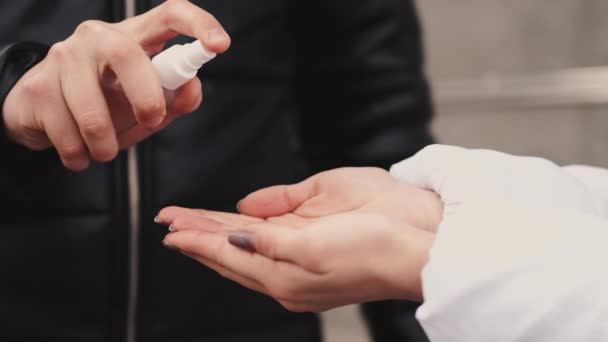 Young people wearing protective masks are spraying hand sanitizer — Stock Video