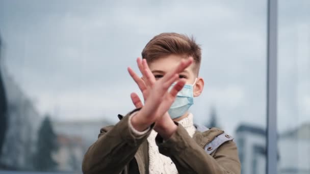 Een jongen met een wegwerpmasker die armen kruist. — Stockvideo