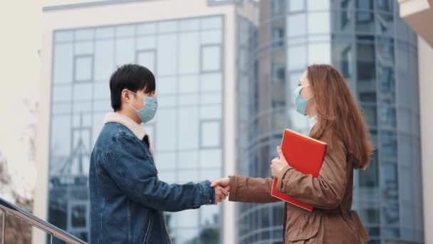 Homme chinois et une femme en masques jetables serrent la main — Video