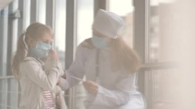 Doktor ve koruyucu maskeli bir çocuk hastanedeler.