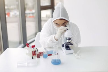 Takım elbiseli laboratuvar çalışanı mikroskobu ayarlıyor.