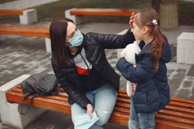 Tek kullanımlık maskeli bir kadın çocuğuna solunum cihazı takmayı öğretiyor.