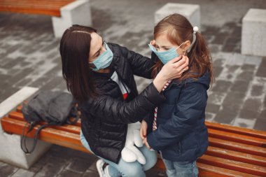 Tek kullanımlık maskeli bir kadın çocuğuna solunum cihazı takmayı öğretiyor.